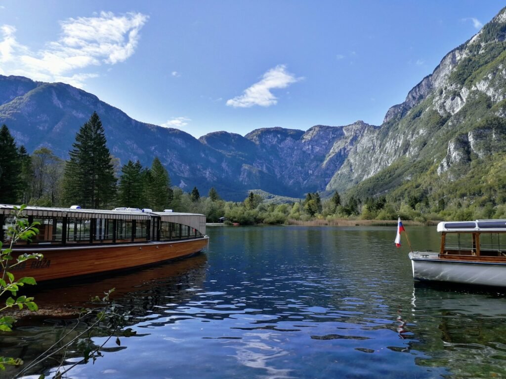 brown boat on calm body of water near mountain