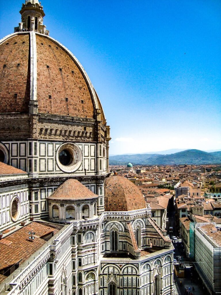 Brown and White Painted Cathedral Roof Overlooking City and Mountain Under Blue Sky